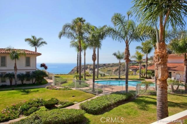 view of pool with a lawn and a water view