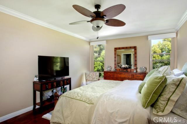 bedroom with dark hardwood / wood-style floors, multiple windows, crown molding, and ceiling fan