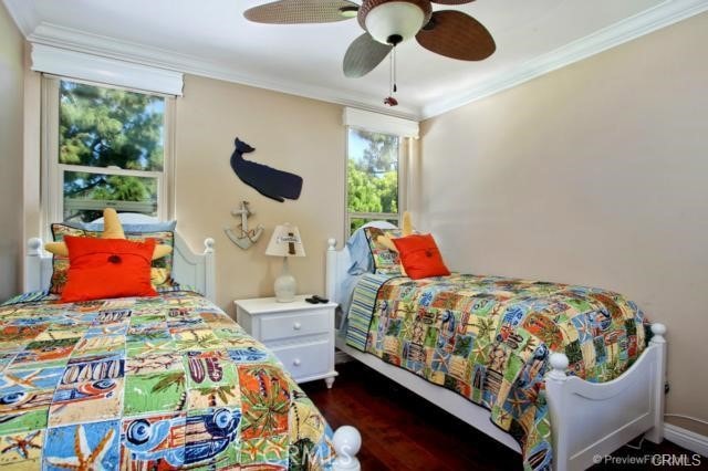 bedroom with dark wood-type flooring, ceiling fan, and ornamental molding