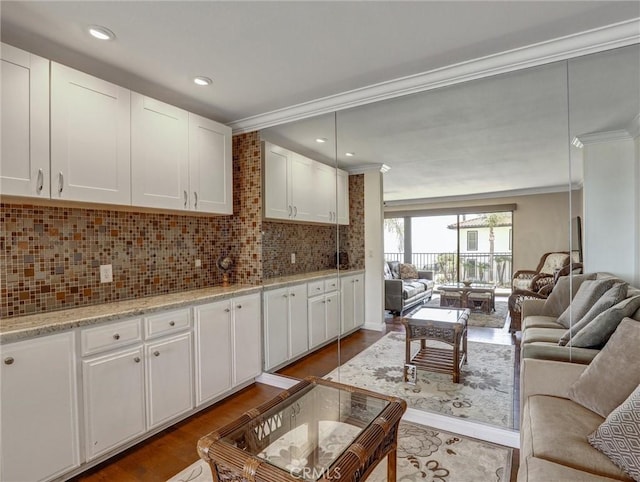 kitchen with decorative backsplash, white cabinetry, open floor plan, and ornamental molding