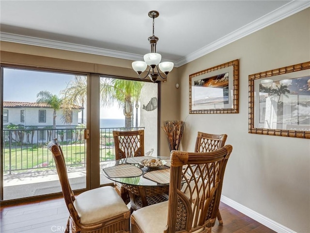 dining space with dark wood finished floors, ornamental molding, baseboards, and a notable chandelier
