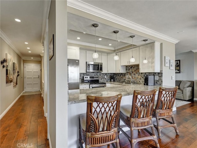 kitchen with a peninsula, backsplash, appliances with stainless steel finishes, and a sink