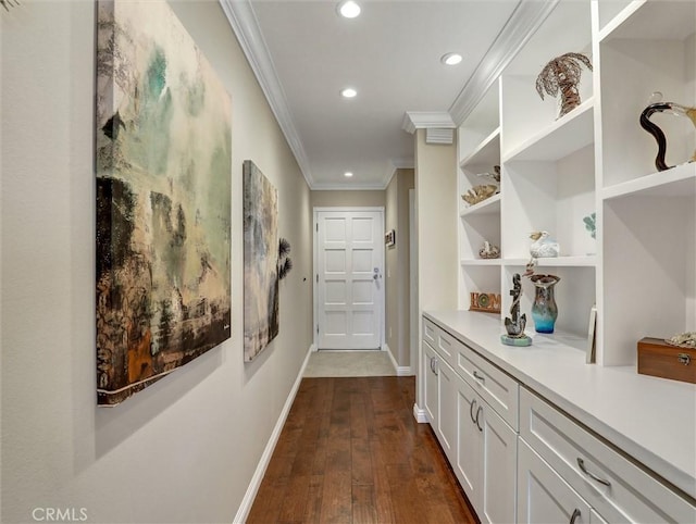 hallway featuring crown molding, built in shelves, baseboards, dark wood-style floors, and recessed lighting