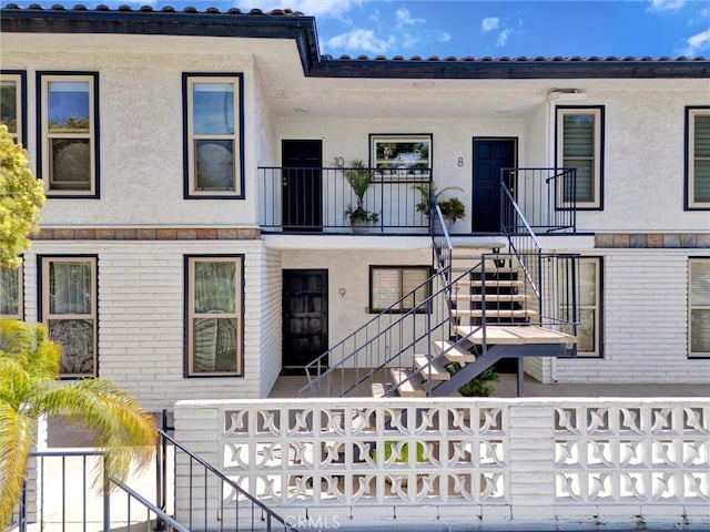 multi unit property with stairs, stucco siding, and fence