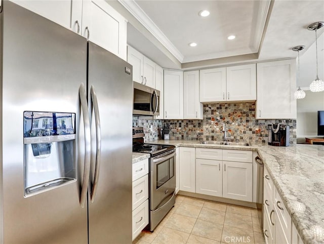 kitchen featuring a tray ceiling, a sink, backsplash, appliances with stainless steel finishes, and ornamental molding