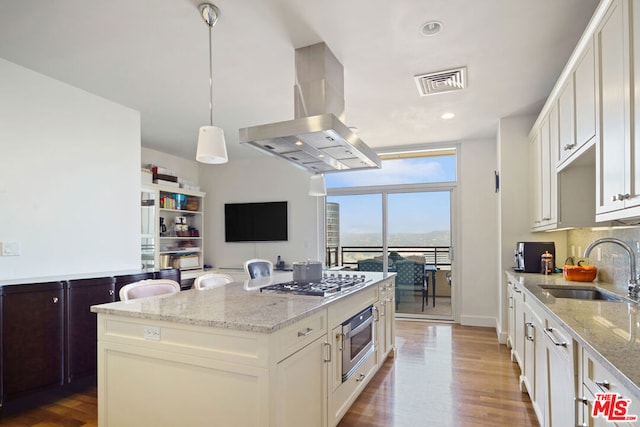 kitchen with island range hood, hanging light fixtures, hardwood / wood-style floors, and a center island