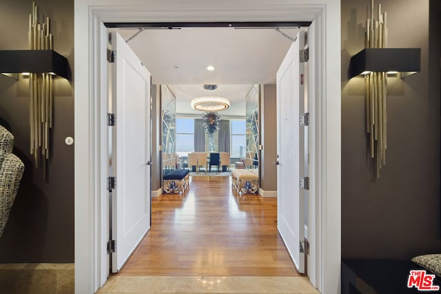 corridor featuring french doors, light hardwood / wood-style flooring, and a chandelier