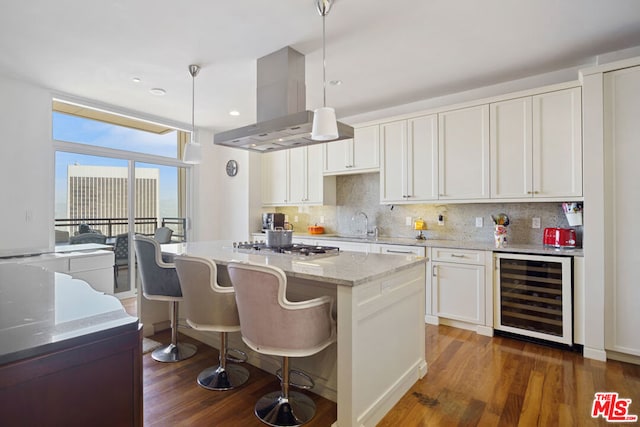 kitchen with white cabinets, beverage cooler, decorative light fixtures, and island exhaust hood