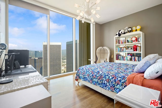 bedroom featuring an inviting chandelier, multiple windows, a wall of windows, and hardwood / wood-style floors