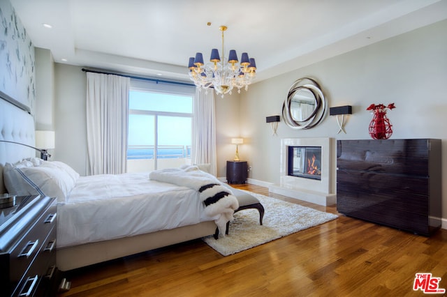 bedroom featuring wood-type flooring, a notable chandelier, and a water view