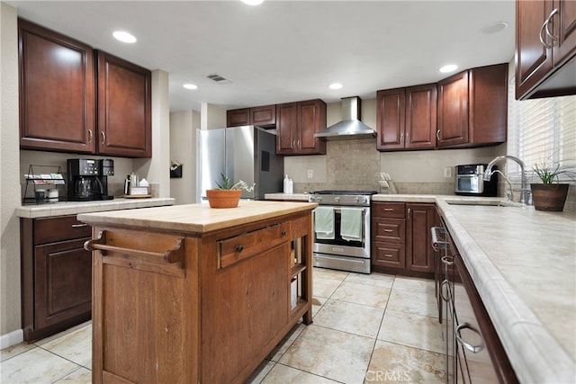 kitchen with a center island, sink, wall chimney exhaust hood, stainless steel appliances, and dark brown cabinetry