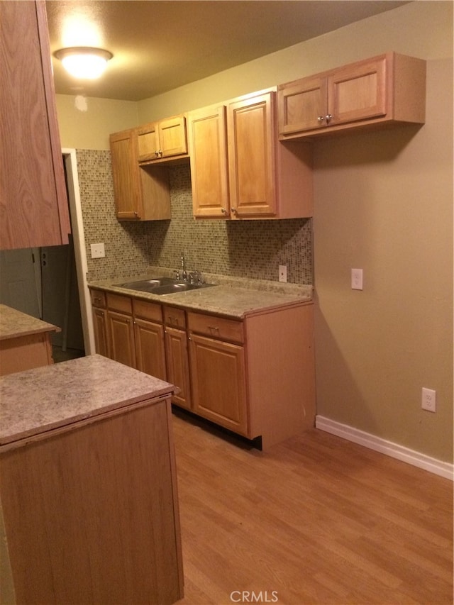 kitchen with backsplash, light hardwood / wood-style floors, sink, and light brown cabinets