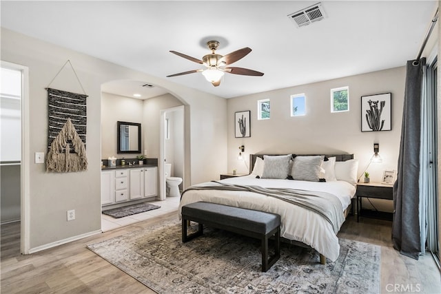 bedroom featuring ceiling fan, light wood-type flooring, and ensuite bath