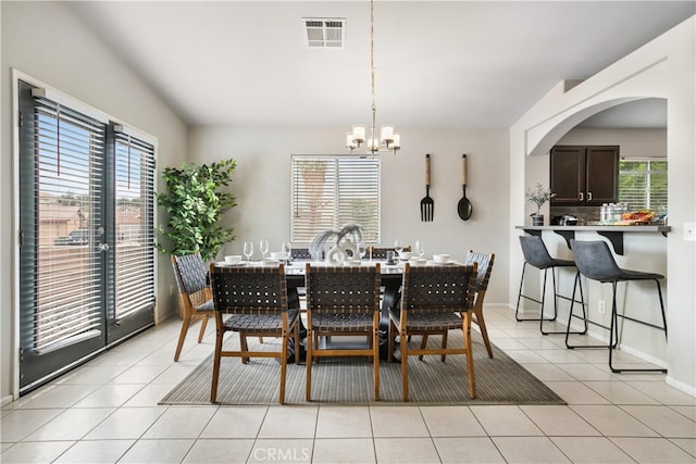 tiled dining room with a notable chandelier and a healthy amount of sunlight