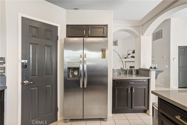 kitchen with dark brown cabinets, light tile patterned floors, and stainless steel fridge with ice dispenser