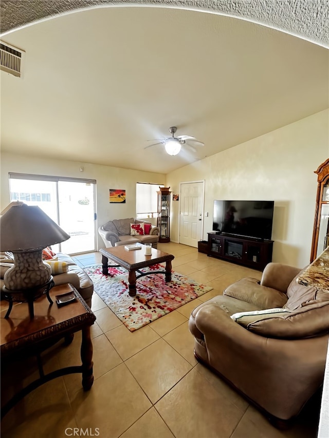 living room featuring lofted ceiling, ceiling fan, and light tile patterned floors