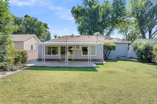 back of house with a lawn and a patio