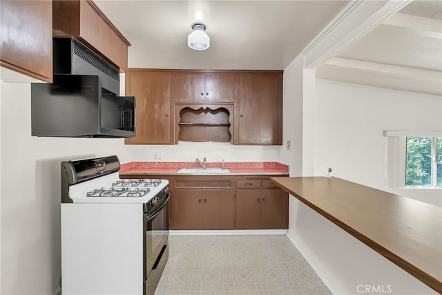 kitchen featuring white range, beam ceiling, and sink