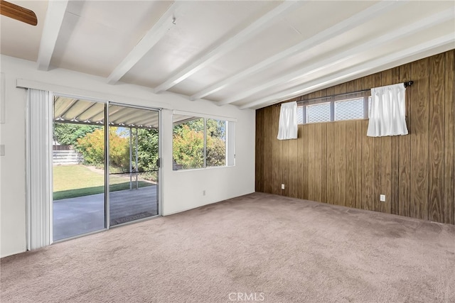 carpeted empty room featuring wooden walls and beam ceiling