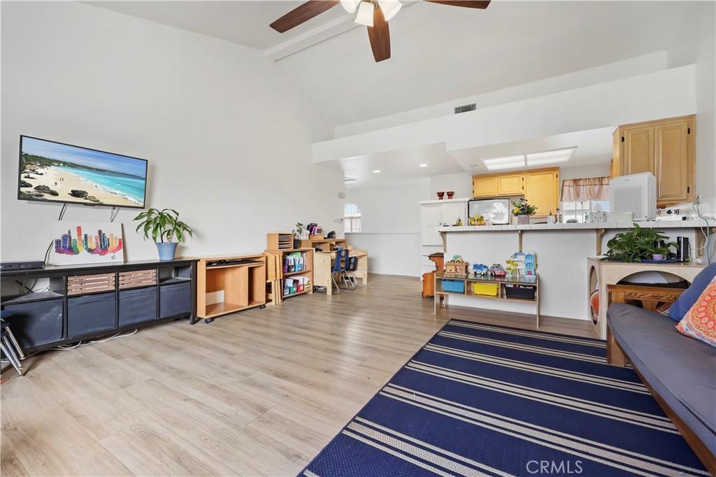 living room with beamed ceiling, ceiling fan, light wood-type flooring, and high vaulted ceiling