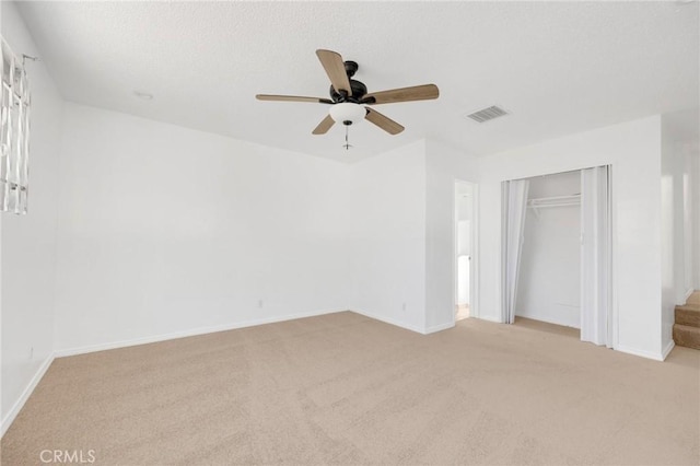 unfurnished bedroom featuring ceiling fan, light carpet, and a closet