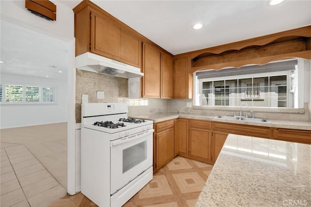 kitchen with white range with gas stovetop, sink, and tasteful backsplash