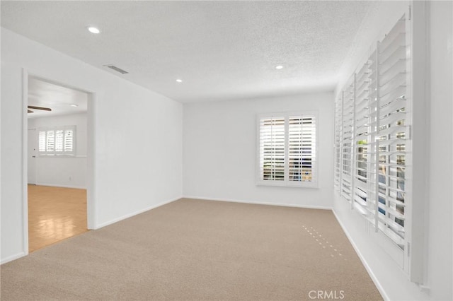 carpeted spare room featuring ceiling fan, a healthy amount of sunlight, and a textured ceiling