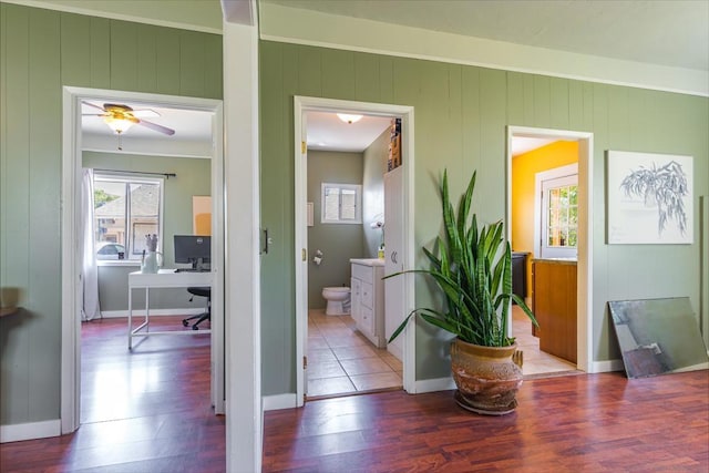 hallway featuring wood walls, wood-type flooring, and ornamental molding