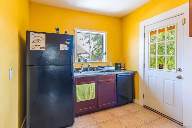 kitchen with black appliances, light tile patterned floors, and sink