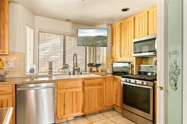 kitchen with sink, light tile patterned floors, backsplash, and appliances with stainless steel finishes