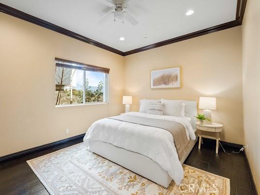 bedroom featuring ceiling fan, ornamental molding, and dark wood-type flooring