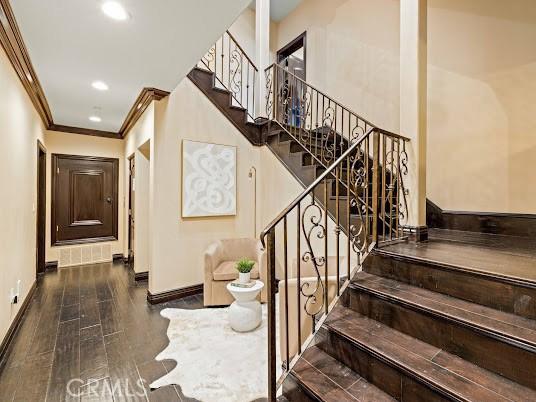 stairway featuring crown molding and wood-type flooring