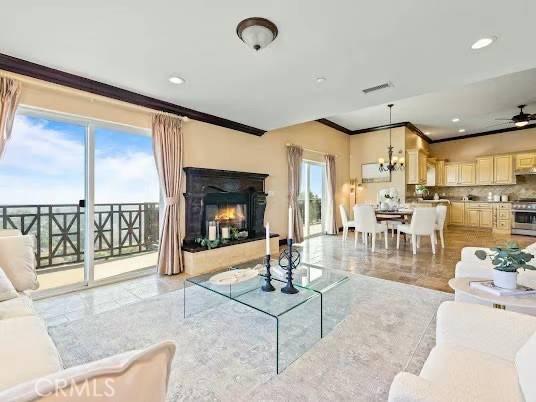 living room with plenty of natural light, ornamental molding, and ceiling fan