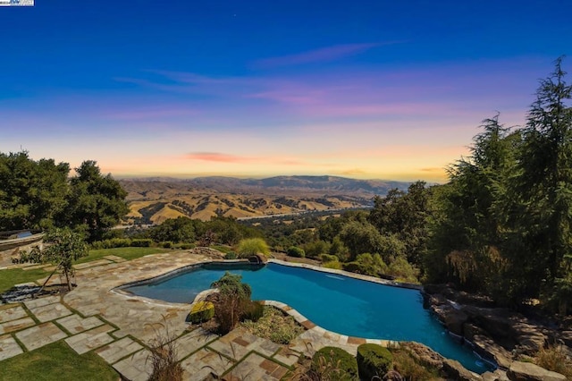 pool at dusk with a patio area and a mountain view