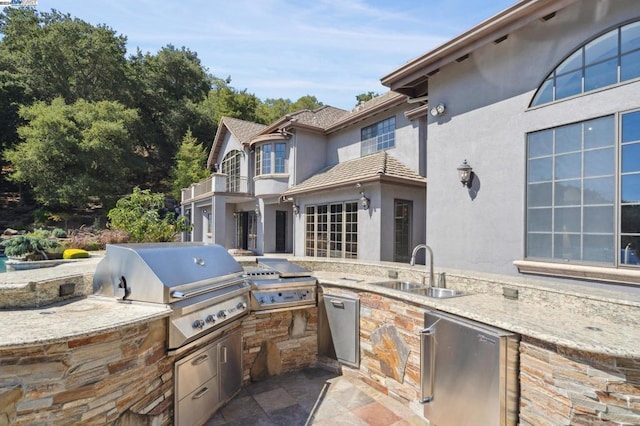 view of patio / terrace featuring area for grilling, sink, a balcony, and exterior kitchen