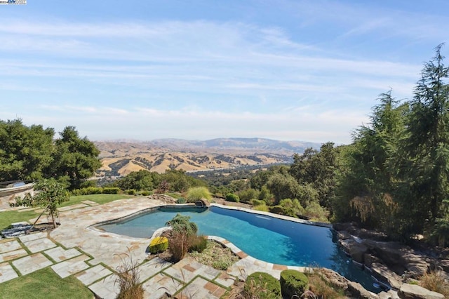 view of pool with a mountain view and a patio