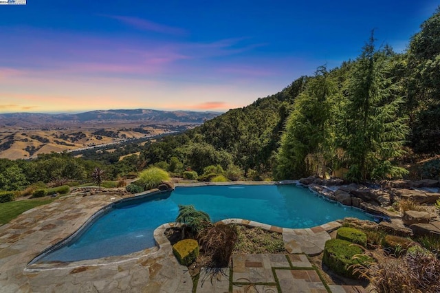 pool at dusk with a mountain view and a patio