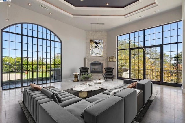 living room with a large fireplace, a raised ceiling, a towering ceiling, and ornamental molding