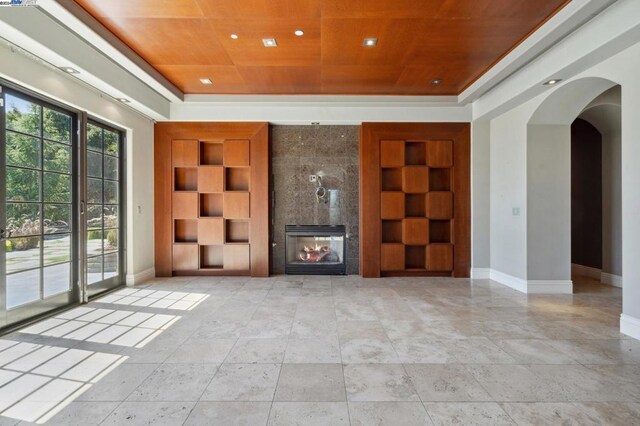 unfurnished living room featuring built in features, a fireplace, and wood ceiling