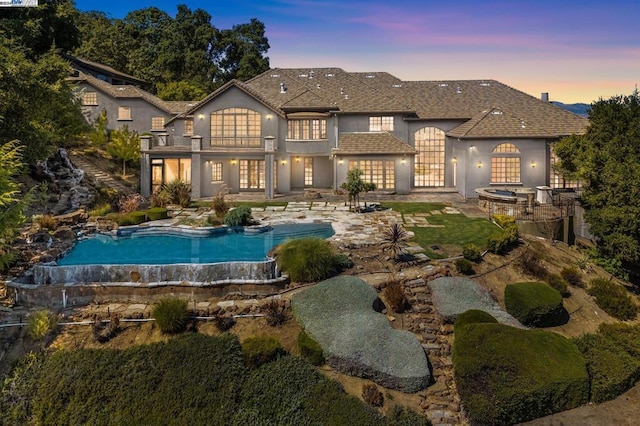 back house at dusk featuring a swimming pool with hot tub, french doors, and a patio