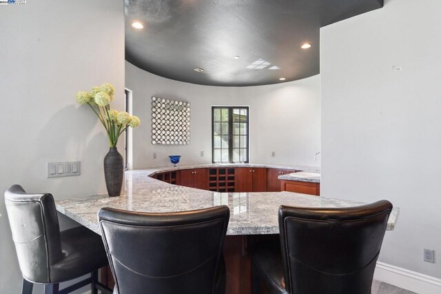 kitchen with a breakfast bar, light stone countertops, and kitchen peninsula