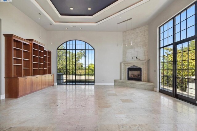 unfurnished living room featuring a raised ceiling, a towering ceiling, and a premium fireplace