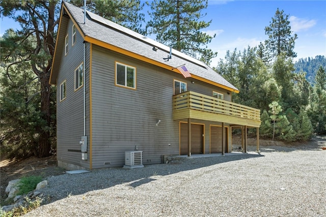 back of property featuring a balcony, a garage, and central AC unit