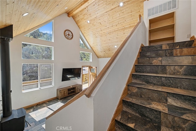 staircase featuring wood ceiling, a wood stove, and high vaulted ceiling