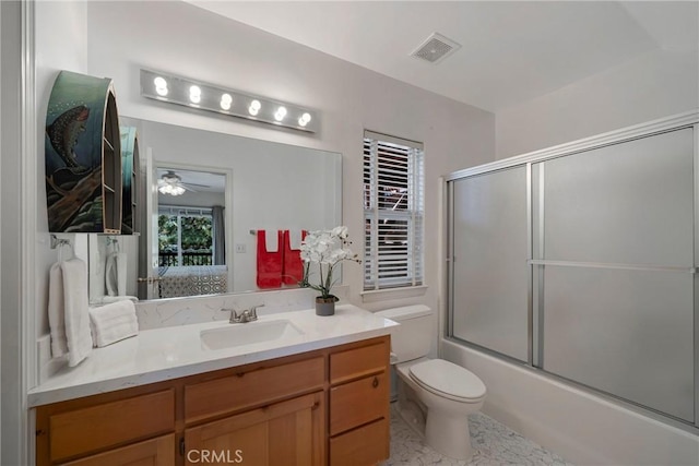 full bathroom featuring vanity, ceiling fan, toilet, and bath / shower combo with glass door