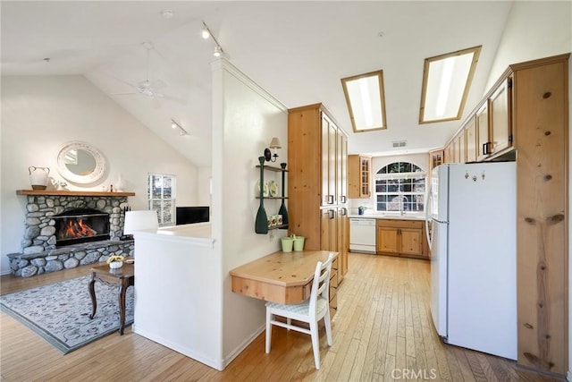 kitchen featuring ceiling fan, light hardwood / wood-style flooring, high vaulted ceiling, white appliances, and a fireplace