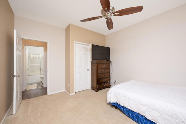 bedroom with ceiling fan, light colored carpet, and ensuite bathroom