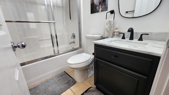 full bathroom with tile patterned floors, bath / shower combo with glass door, vanity, and toilet