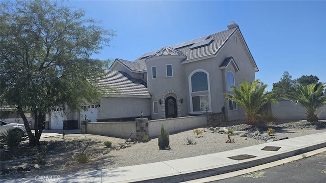 view of front of property with solar panels, a tile roof, an attached garage, fence, and stucco siding