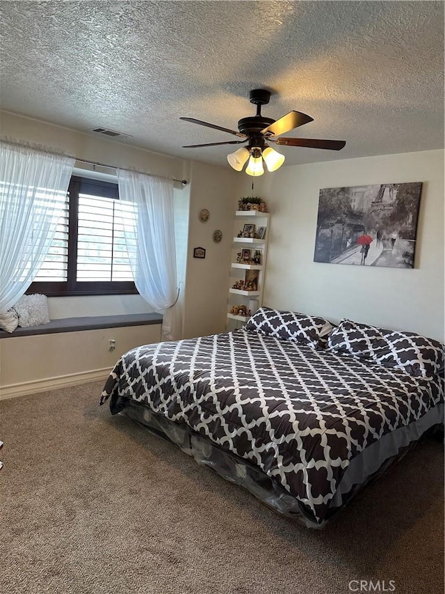 bedroom featuring carpet, visible vents, ceiling fan, and a textured ceiling